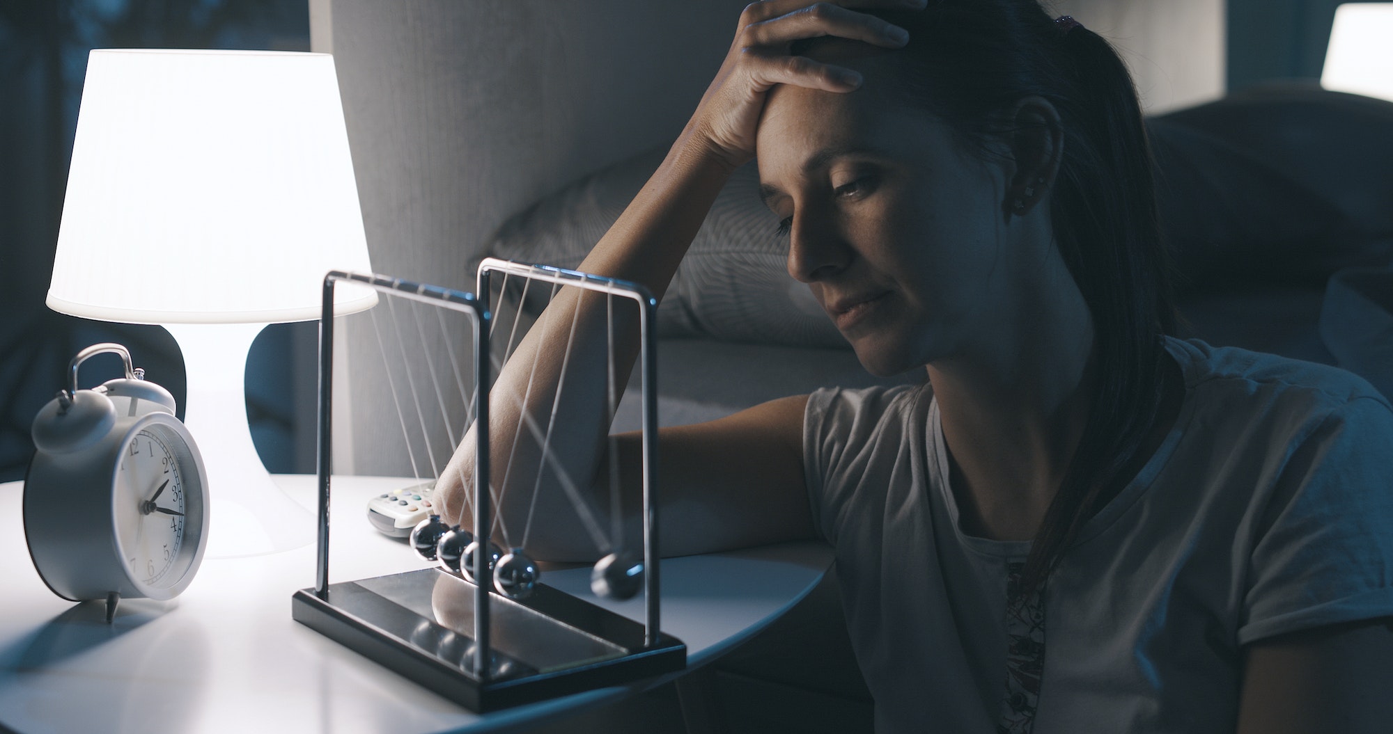 Sad woman suffering from insomnia and staring at Newton's cradle