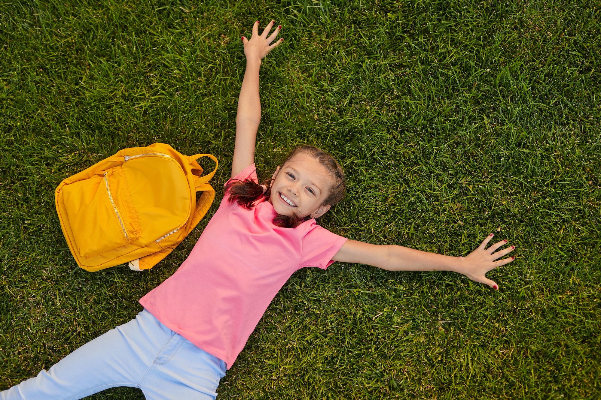 Smiling schoolgirl lying on grass during break