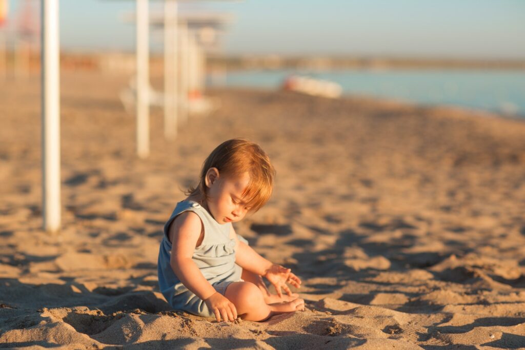 Baby child on beach on sea play with sand in summer