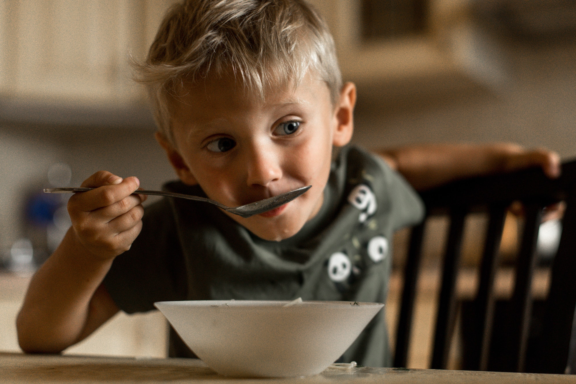 4 year old boy is having lunch. Child eating soup