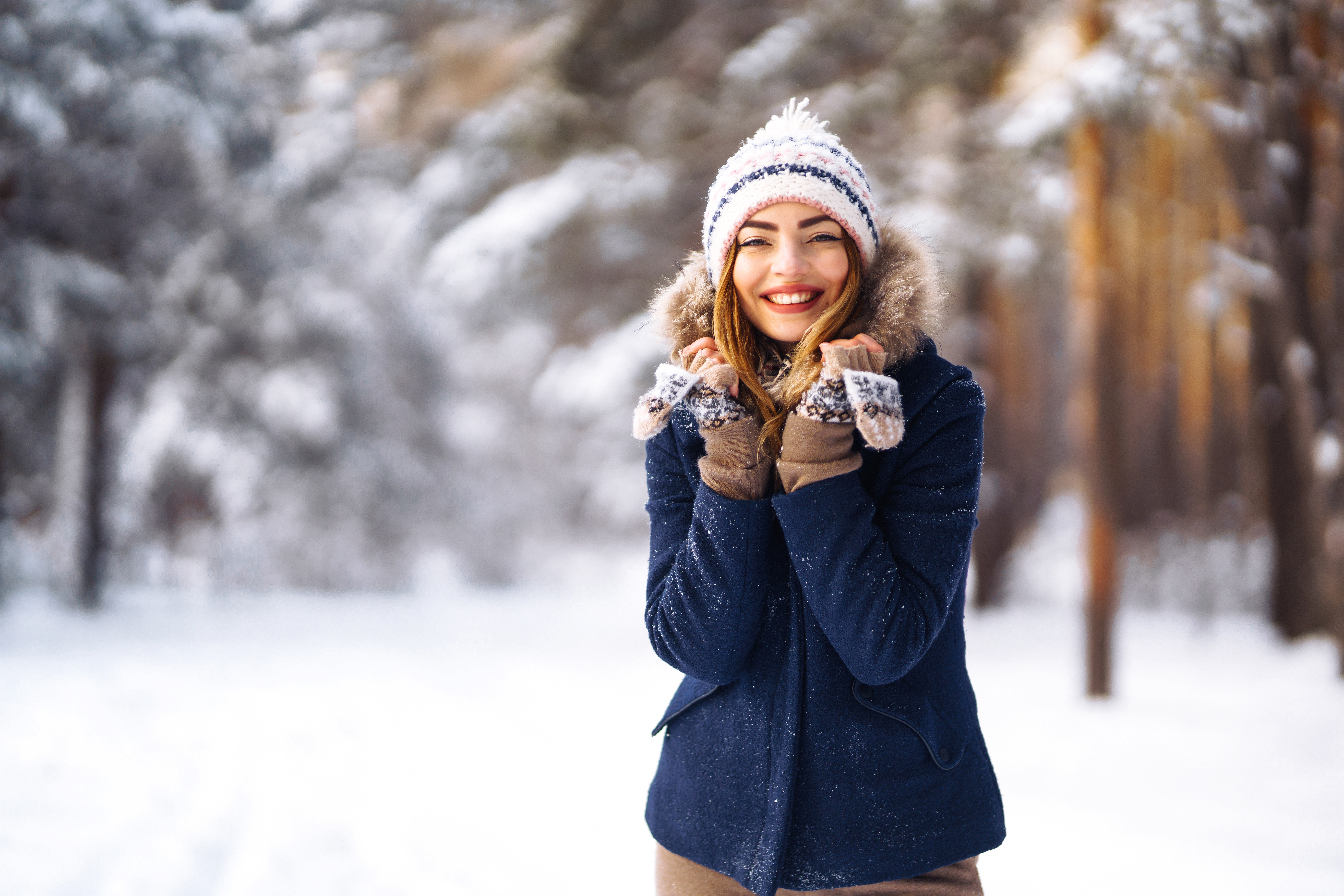 Happy young woman plays with a snow in sunny winter day. Girl enjoys winter, frosty day.